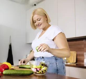 Frau mit blonden Haaren bereitet in moderner K&uuml;che einen frischen Salat zu &ndash; Symbolbild f&uuml;r gesunde Ern&auml;hrung beim Abnehmen.