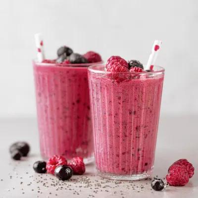 Zwei Gläser mit pinkfarbenem Beeren-Smoothie, dekoriert mit Himbeeren und Heidelbeeren sowie Trinkhalmen.