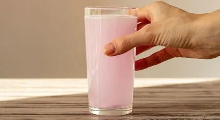 Hand hält ein Glas mit rosa Elektrolytgetränk – Flüssigkeitszufuhr und Mineralstoffversorgung im Fokus
