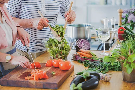 Zwei Personen bereiten gemeinsam eine gesunde Mahlzeit aus frischem Gemüse in einer modernen Küche zu.