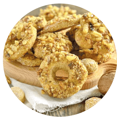 Kringelf&ouml;rmige Kekse mit N&uuml;ssen bestreut auf einem Holzbrett &ndash; weihnachtliches Gew&uuml;rzgeb&auml;ck mit Nusskruste.