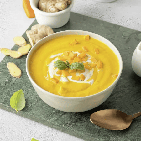 Cremige Karottensuppe mit Ingwer und frischen Kr&auml;utern serviert