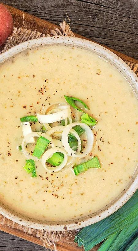 Lauchsuppe mit Kartoffeln in Keramiksch&uuml;ssel, garniert mit frischen Lauchringen und Gew&uuml;rzen