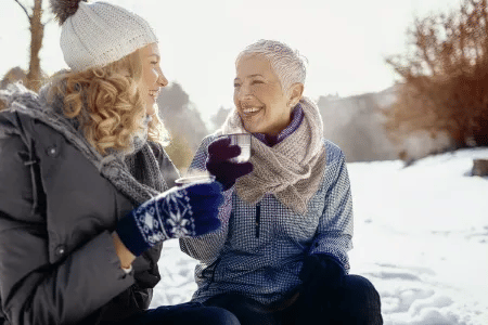 Zwei Frauen genießen gemeinsam einen warmen Tee im verschneiten Winter.
