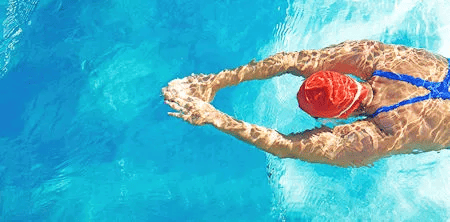 Schwimmerin mit roter Badekappe gleitet durch klares blaues Wasser