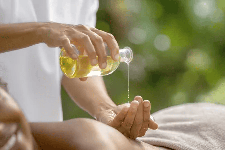 Nahaufnahme von Massage&ouml;l, das in eine Hand gegossen wird